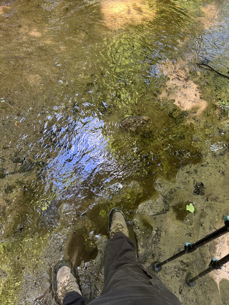 Beneath every step | Christian desires | Boots standing on a creek bank.